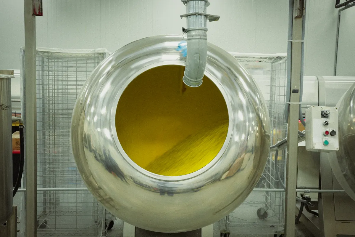 Front view of a polished stainless-steel drum with a circular opening and a pipe entering from above.